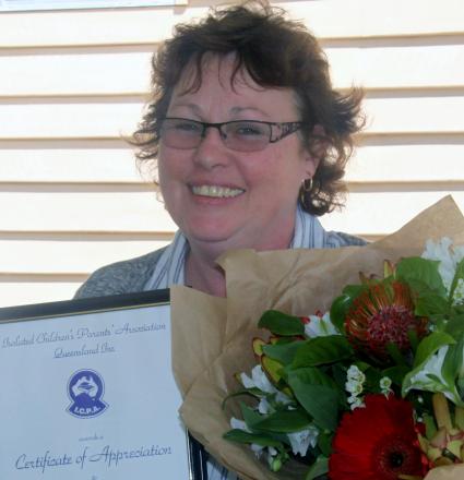 picture of Carmel holding flowers and certificate