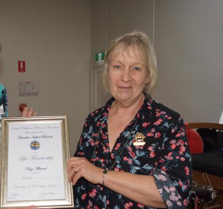 lady with blonde hair and flower shirt with certificate