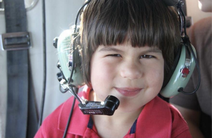 Small child with headset on in helicopter.