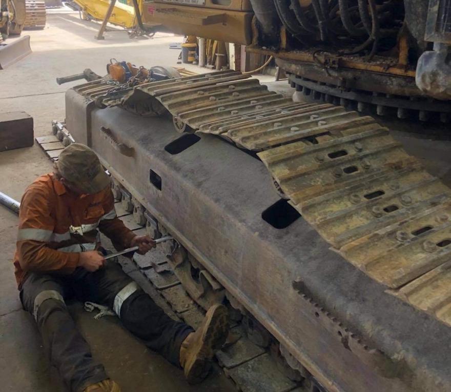 An apprentice working on a dozer track