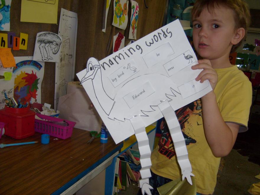 A boy holding a poster in a classroom