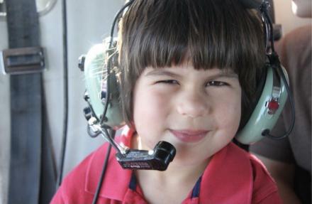 Small child with headset on in helicopter. 