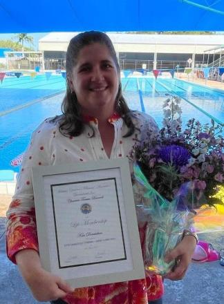 picture of Kim holding flowers and certificate