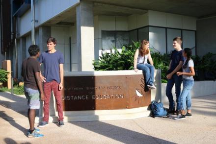 Students standing in front of Northern Territory School of Distance Education sign